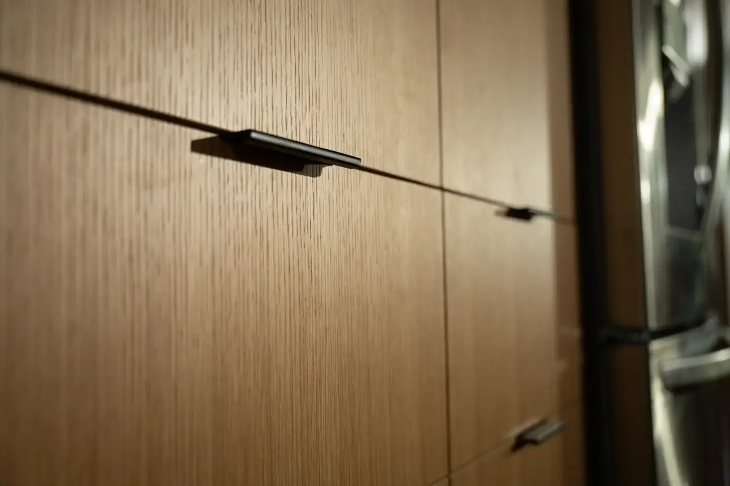 Close-up of straight-grain white oak cabinet faces with slim black pulls