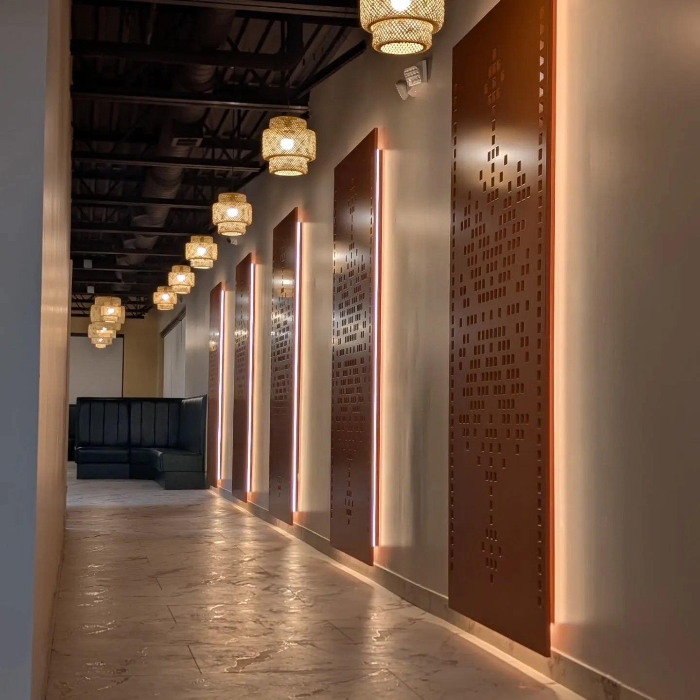 Backlit CNC-perforated copper feature-wall panels in a hospitality corridor