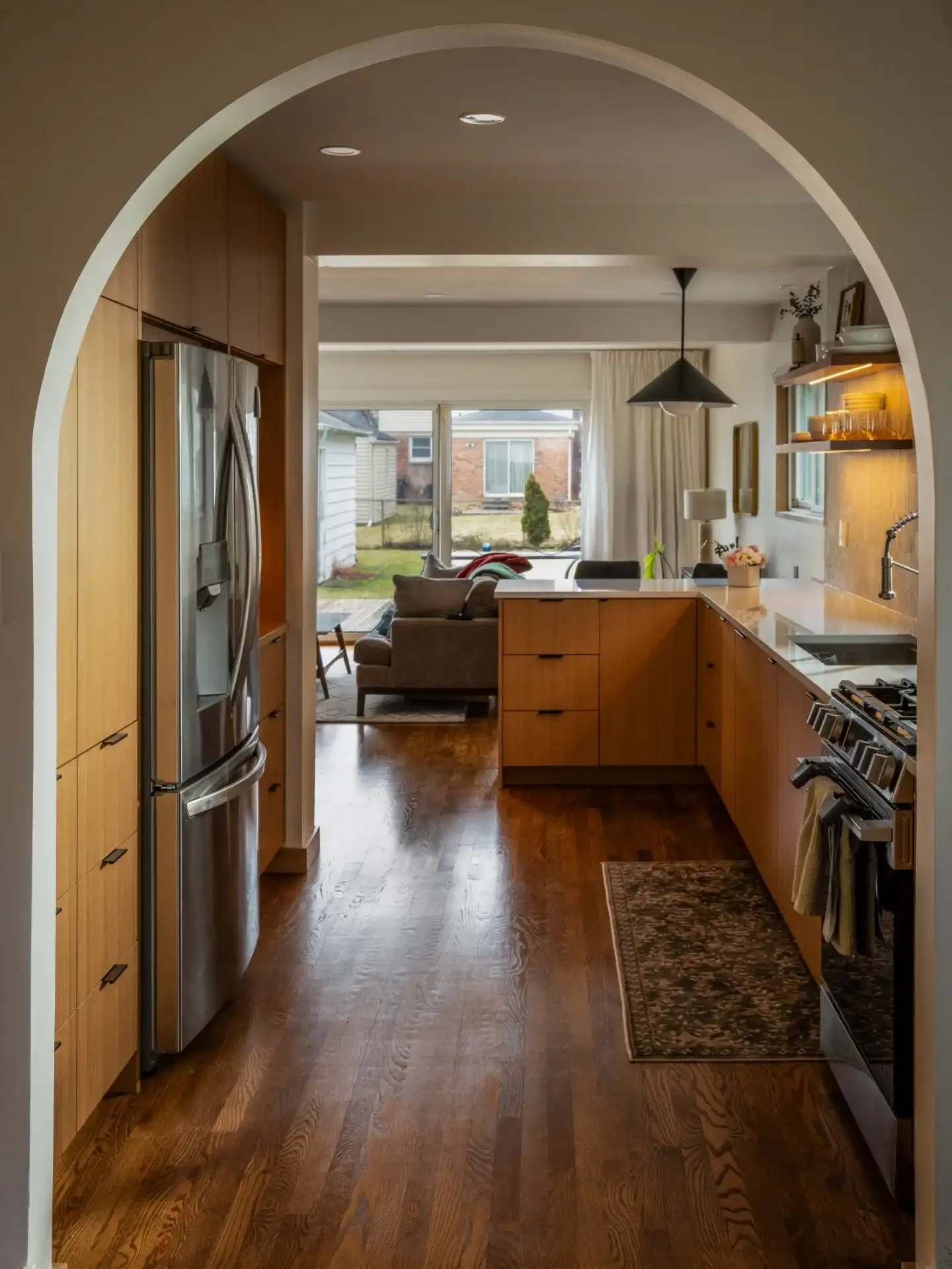 Custom rift white oak kitchen cabinetry seen through an arched opening